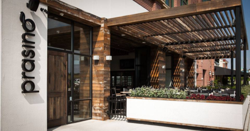 Exterior view of Prasino restaurant featuring wooden accents, outdoor seating, and a modern design.
