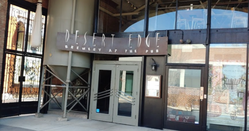 Entrance to Desert Edge Brewery at the Pub, featuring a large sign and modern glass doors.
