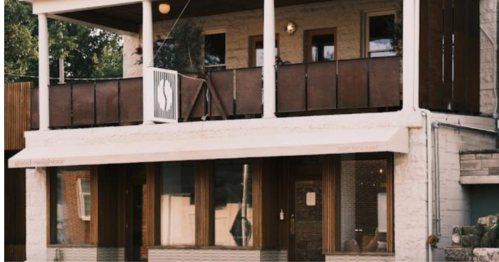 A two-story building with a balcony, featuring large windows and a sign that reads "good neighbor."
