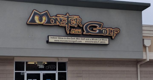 Sign for Monster Mini Golf featuring indoor glow-in-the-dark mini golf, with a playful monster-themed design.