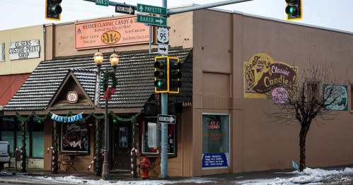 A street corner featuring a candy shop, traffic lights, and a snowy sidewalk.