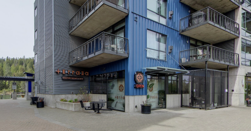 Modern building exterior with balconies, featuring a sign for "Terraza Waterfront" and an open entrance.