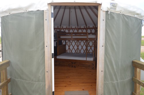 Interior of a yurt showing wooden floors, a bunk bed, and a cozy, rustic design.