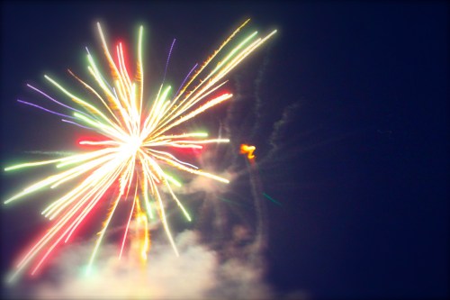 Colorful fireworks burst in the night sky, creating a vibrant display of light and color against a dark background.