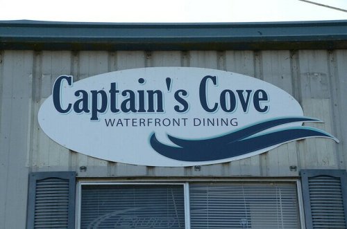 Sign for "Captain's Cove" featuring the text "WATERFRONT DINING" with a wave graphic below.