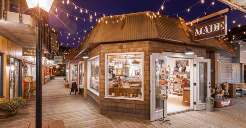 A charming wooden storefront at night, adorned with string lights, showcasing various items inside.