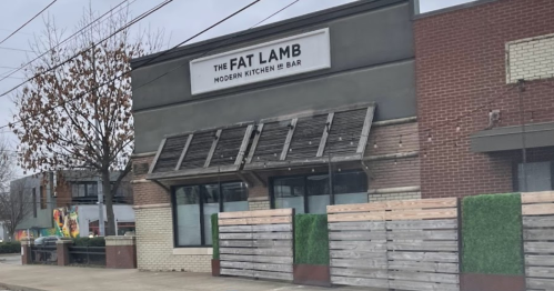 Exterior of "The Fat Lamb" restaurant featuring a modern design, large windows, and wooden fencing.