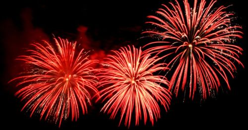 Bright red fireworks explode against a dark night sky, creating a festive and vibrant display.
