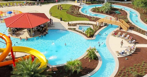 Aerial view of a vibrant water park with slides, lazy river, and people enjoying the pool area.