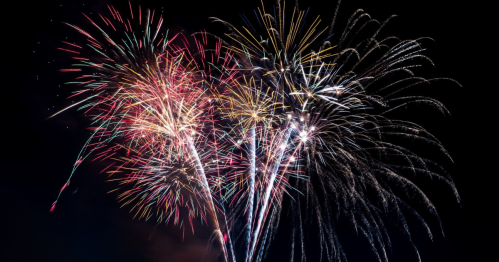 Colorful fireworks burst in the night sky, creating a vibrant display of light and patterns.