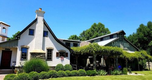 A charming building with a sloped roof, surrounded by greenery and a clear blue sky, featuring a sign that reads "Cedar Creek."