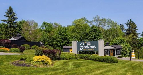 Sign for Seascape Hotel & Cottages surrounded by lush greenery and colorful landscaping on a sunny day.