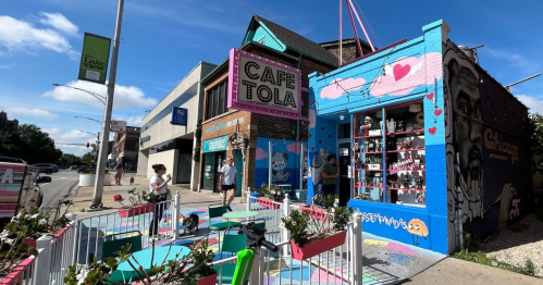 Colorful exterior of Café Tola with vibrant murals, outdoor seating, and people enjoying the lively atmosphere.