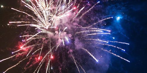 Colorful fireworks explode in the night sky, creating a vibrant display of light and color.