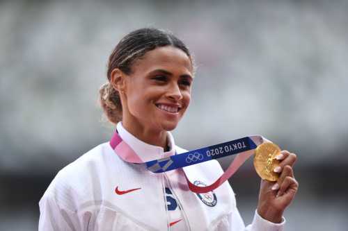 Athlete proudly displays her gold medal at the Tokyo 2020 Olympics, smiling with a medal around her neck.