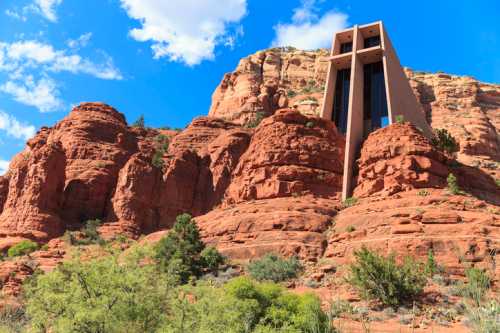 A modern building stands against a backdrop of red rock formations and blue skies in a desert landscape.