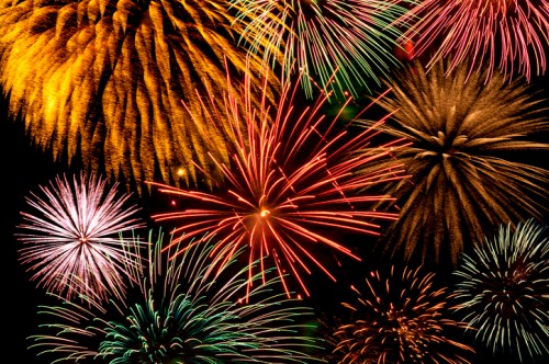 A vibrant display of colorful fireworks bursting in the night sky, featuring various shapes and patterns.