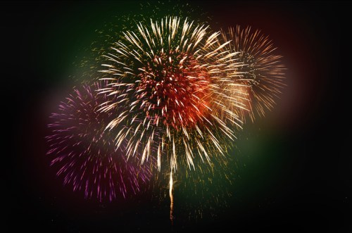 Colorful fireworks explode in a night sky, creating a vibrant display of light and color.