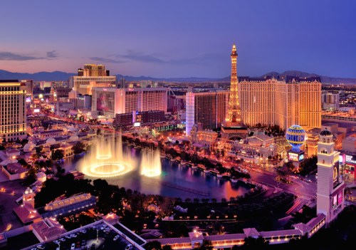 Aerial view of the Las Vegas Strip at dusk, featuring illuminated buildings and the Bellagio fountains.