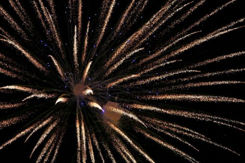 Colorful fireworks burst in a dark sky, creating a dazzling display of light and sparks.