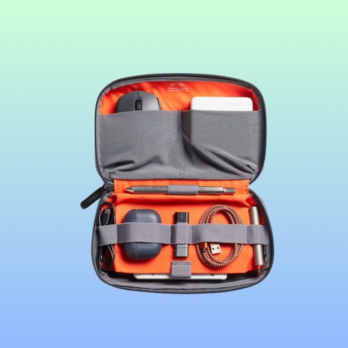 A gray tech organizer case opened to reveal a mouse, pen, USB drive, and cables on an orange interior.
