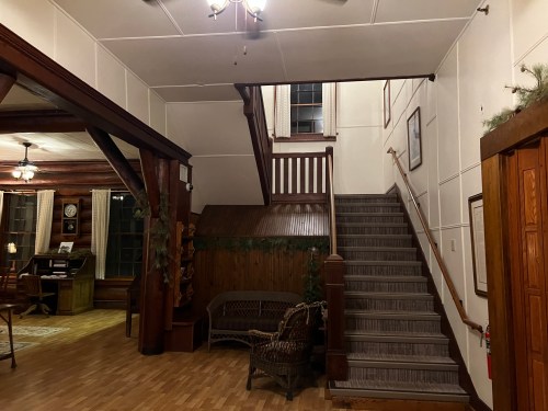 A cozy interior featuring a staircase, wooden beams, and a seating area with a rustic charm.