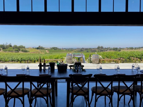 A spacious dining area with a view of vineyards and rolling hills under a clear blue sky.