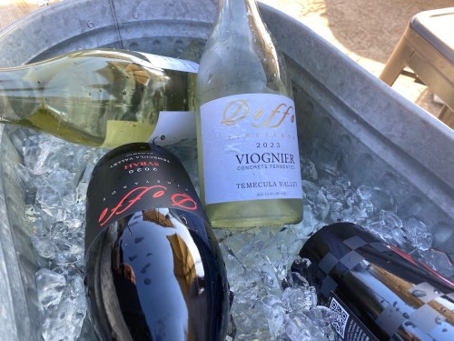 A metal tub filled with ice, featuring bottles of red and white wine.