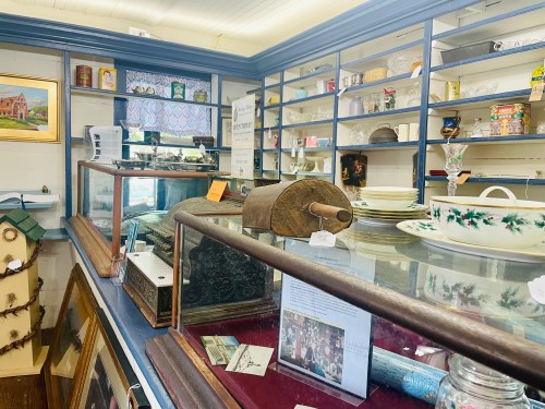 A vintage shop display featuring glass cases, shelves of dishes, and various antiques.