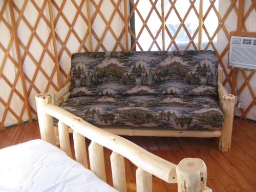 A cozy yurt interior featuring a wooden-framed sofa with a nature-themed fabric and an air conditioning unit.