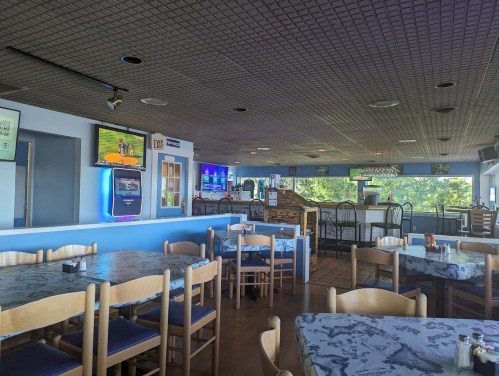 Interior of a casual dining restaurant with tables, chairs, and multiple TVs displaying sports. Bright and inviting atmosphere.