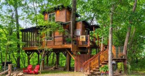 A rustic treehouse Airbnb surrounded by tall green trees. This is one of the most unique stays in Kansas.