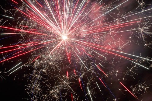 Colorful fireworks burst in the night sky, creating a dazzling display of red, white, and blue sparks.