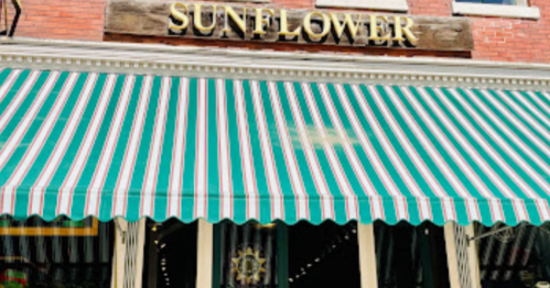 A storefront with a green and white striped awning and a sign that reads "SUNFLOWER" above the entrance.