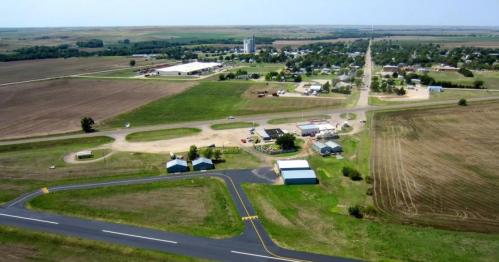 Aerial view of a small town with fields, roads, and buildings, showcasing rural landscape and community layout.