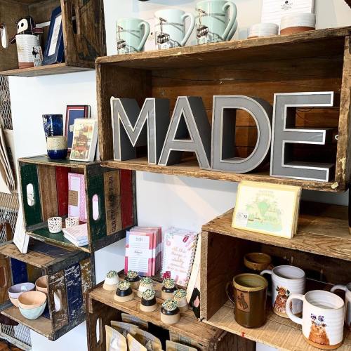 A display of wooden shelves filled with various handmade items, featuring the word "MADE" in large letters.