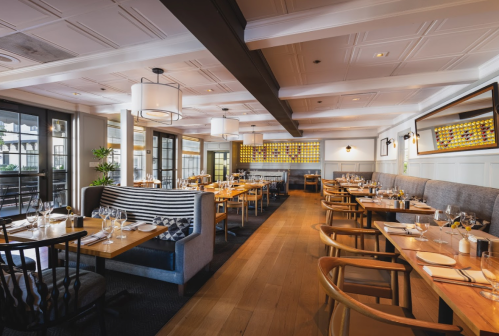 A modern restaurant interior with wooden tables, stylish seating, and bright lighting, creating a welcoming atmosphere.