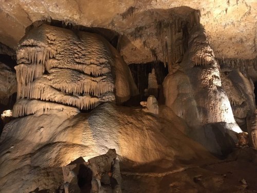 Stalactites and stalagmites in a dimly lit cave, showcasing unique rock formations and textures.
