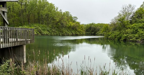 Wooden fishing dock overlooking the quiet, tree-lined waters of Osprey Lake in Illinois.