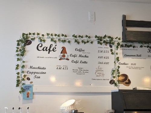 Café menu featuring drinks like macchiato, cappuccino, and pastries, decorated with green vines.