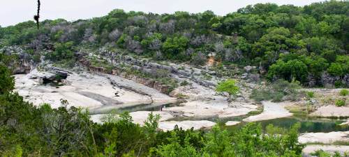 A serene landscape featuring rocky terrain, lush greenery, and a calm river winding through the scene.