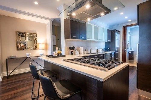 Modern kitchen with a central island, sleek cabinetry, and stainless steel appliances, featuring stylish bar stools.
