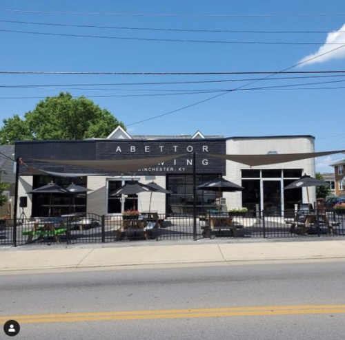 Exterior of Abettor Brewing in Winchester, KY, featuring outdoor seating and a clear blue sky.