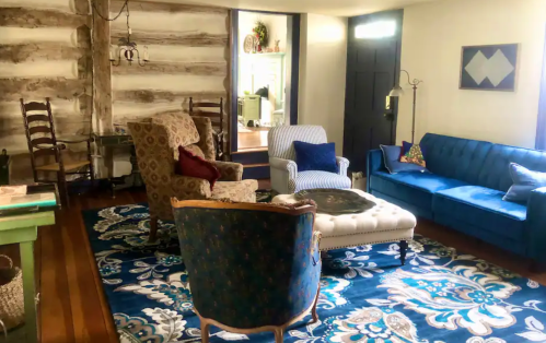 Cozy living room with a blue rug, vintage chairs, and a mix of modern and rustic decor.