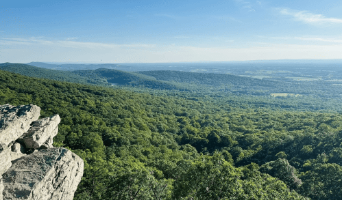 A panoramic view of lush green mountains and valleys under a clear blue sky.