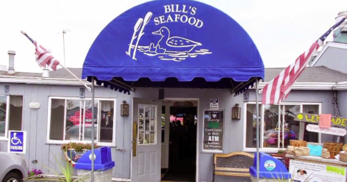 A seafood restaurant entrance with a blue awning featuring a duck logo and American flags outside.