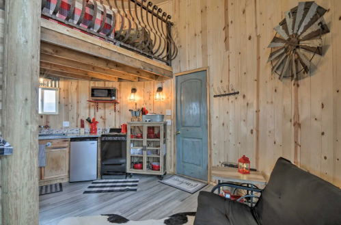 Cozy cabin interior with wooden walls, a lofted bed, kitchenette, and rustic decor.