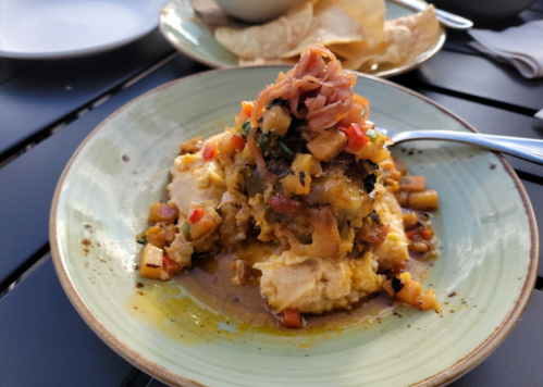 A plate of creamy mashed potatoes topped with a savory meat patty and a colorful vegetable salsa.