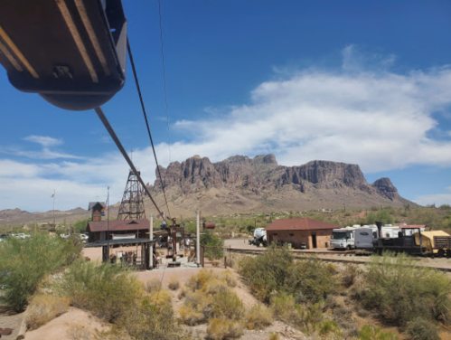 A scenic view of a mountainous landscape with a blue sky, featuring a cable and rustic buildings in the foreground.
