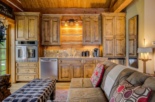 Cozy kitchen with wooden cabinets, granite countertops, and modern appliances, featuring a comfortable sofa in the foreground.